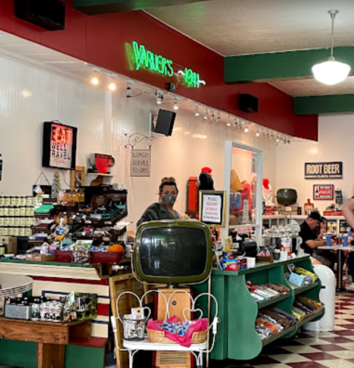 A retro diner interior with a vintage TV, colorful decor, and patrons enjoying their meals at tables.