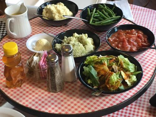 A round table with bowls of mashed potatoes, green beans, rice, tomato sauce, salad, and a side of ice cream.