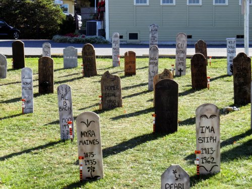A cemetery with various gravestones, some marked with names and dates, set in a grassy area.