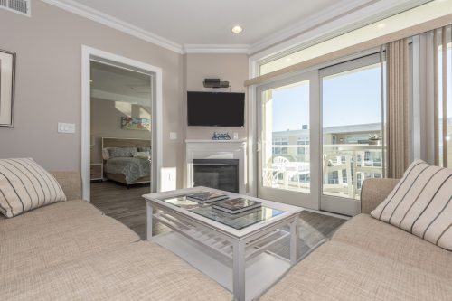 Cozy living area with two sofas, a coffee table, and a TV, featuring large windows and a view of the outdoors.