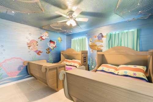 A colorful children's bedroom with two wooden beds, ocean-themed murals, and blue walls decorated with sea creatures.