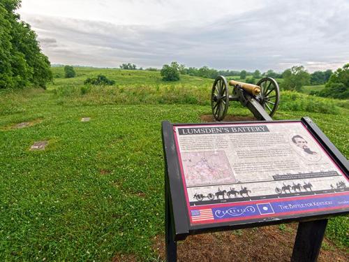 A historic cannon on a grassy field with an informational sign about Lumsden's Battery in the background.