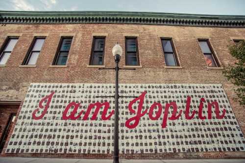 Mural on a brick wall featuring the text "I am Joplin" with numerous small images surrounding it.