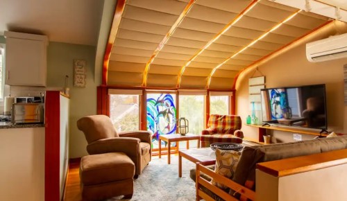Cozy living room with stained glass windows, comfortable seating, and a TV, featuring warm lighting and a modern design.