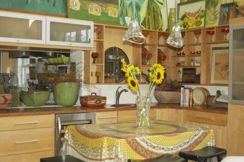 Bright kitchen with wooden cabinets, colorful artwork, and a table adorned with sunflowers in a vase.