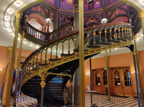 A grand spiral staircase with ornate railings in a beautifully lit interior space.