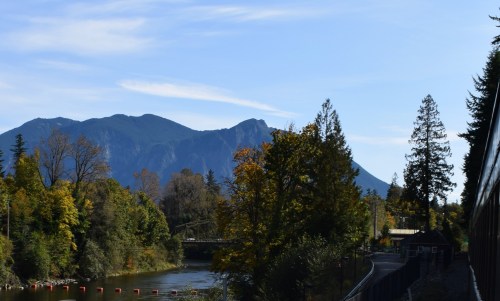 Scenic view of a river surrounded by trees and mountains under a clear blue sky.