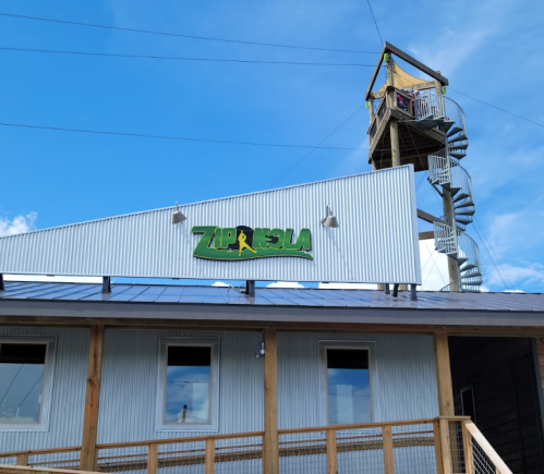 A building with a sign that reads "ZIPRIDE" and a spiral staircase leading to an observation tower against a blue sky.