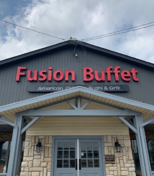 Sign for "Fusion Buffet" featuring American cuisine, sushi, and grill, with a cloudy sky in the background.