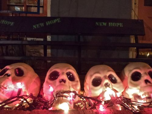 Four skull decorations with black eyes and colorful lights, placed on a bench that reads "NEW HOPE."