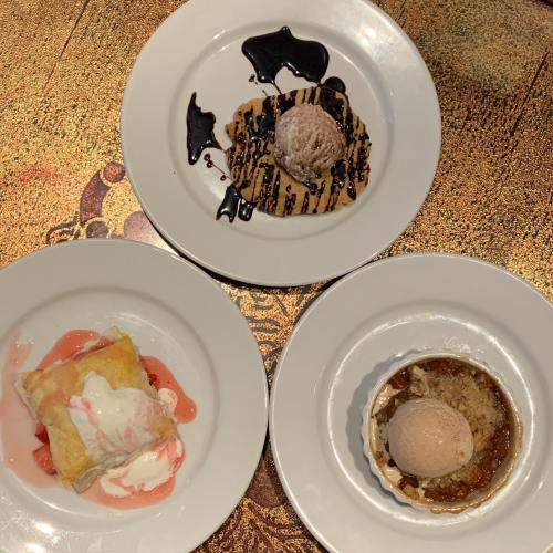 Three dessert plates: a pastry with strawberries and cream, a chocolate-drizzled cookie with ice cream, and a tart with ice cream.