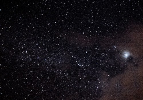 A starry night sky filled with countless stars and a faint cloud, creating a serene cosmic scene.