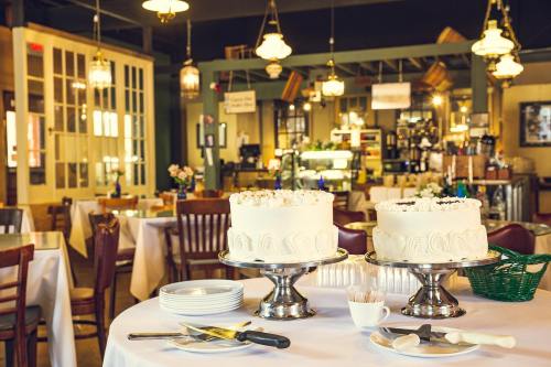 A cozy restaurant interior featuring two elegant cakes on a table, surrounded by chairs and soft lighting.