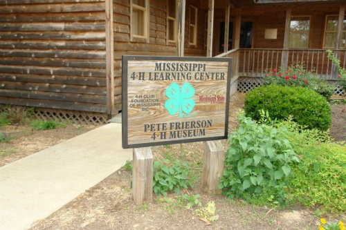 Sign for the Mississippi 4-H Learning Center and Pete Frierson 4-H Museum, set in a rustic outdoor environment.