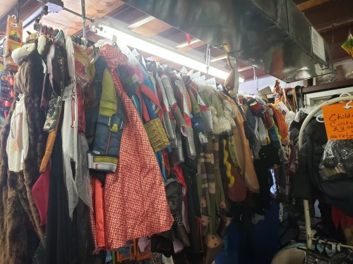 A colorful assortment of costumes hanging on racks in a store, including children's outfits and various themed attire.