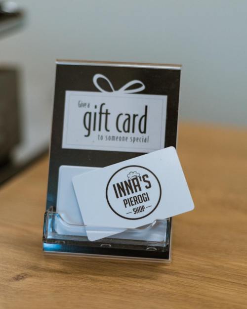 A gift card display featuring a card for Inna's Pierogi Shop on a wooden table.