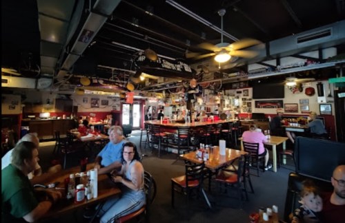A bustling restaurant interior with tables, patrons, and decor featuring memorabilia on the walls.