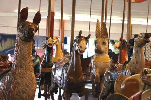 A vintage carousel featuring various intricately carved animals, including horses, a llama, and an owl.