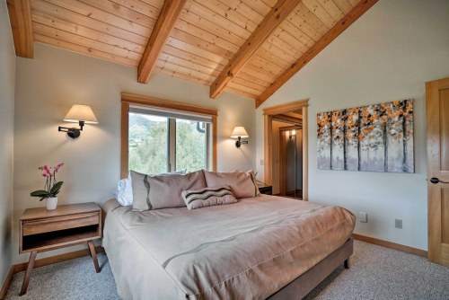 Cozy bedroom with a large bed, wooden beams, and a nature-themed painting on the wall. Soft lighting enhances the ambiance.