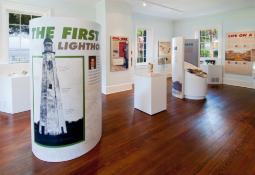 Interior of a museum exhibit featuring cylindrical displays about lighthouses, the Civil War, and local history.