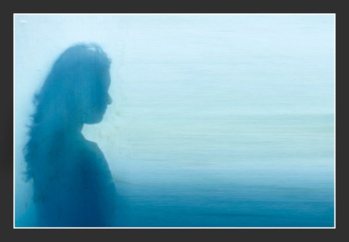 A silhouette of a woman against a soft blue background, creating a dreamy and ethereal effect.