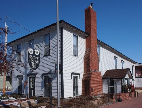 Historic Affront House Inn, a two-story white building with a red brick chimney, set against a clear blue sky.