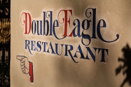 Sign for "Double Eagle Restaurant" with decorative lettering and a pointing hand illustration.