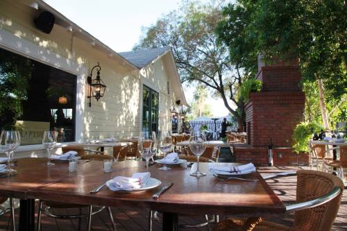Outdoor dining area with a wooden table set for a meal, surrounded by greenery and a charming restaurant exterior.