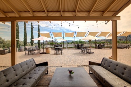 Outdoor seating area with modern sofas, tables, and umbrellas, overlooking a scenic landscape.