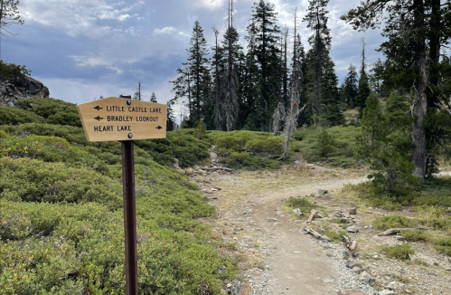 Trail sign pointing to Little Castle Lake, Bradley Lookout, and Heart Lake, surrounded by trees and rocky terrain.
