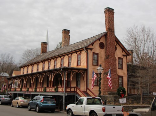 Historic building with a wooden facade, multiple chimneys, and American flags, set in a quaint town.