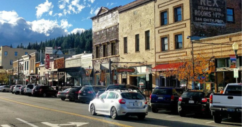 A charming street lined with historic buildings and parked cars under a blue sky with scattered clouds.