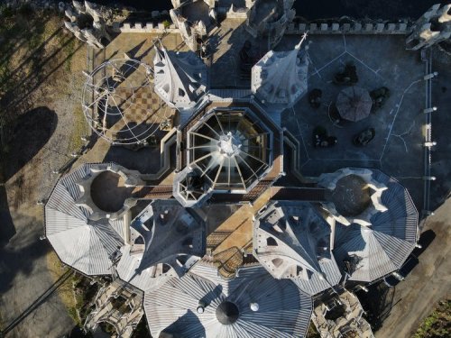 Aerial view of a large, intricate castle with multiple towers and a central dome, surrounded by pathways and gardens.