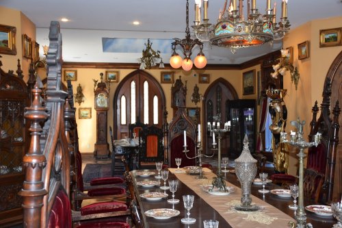 A lavish dining room with ornate furniture, a long table set for a meal, and decorative artwork on the walls.