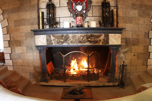 A cozy fireplace with a stone mantel, featuring decorative elements and a warm fire burning inside.