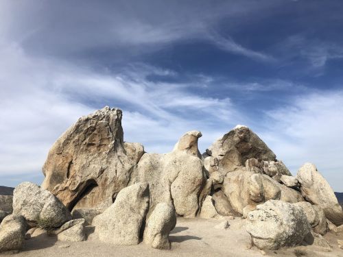 A cluster of large, weathered rocks under a blue sky with wispy clouds.