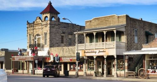 Historic buildings line a street, featuring shops and a distinctive tower with a red roof.