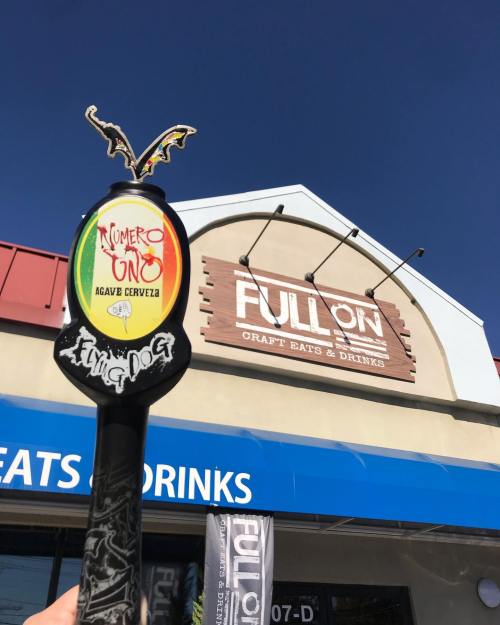 A colorful beer tap handle in front of a restaurant sign that reads "FULL ON Craft Eats & Drinks."