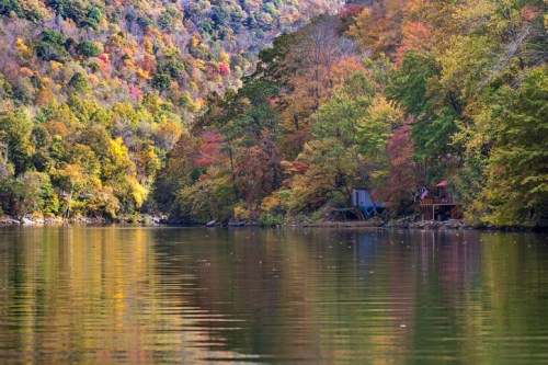 A serene lake surrounded by vibrant autumn foliage reflecting on the water's surface.