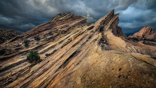 Dramatic rock formations under a moody sky, showcasing layered textures and earthy tones.
