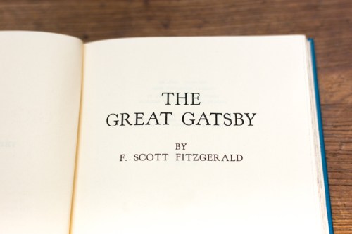 Open book page displaying the title "The Great Gatsby" by F. Scott Fitzgerald on a wooden surface.