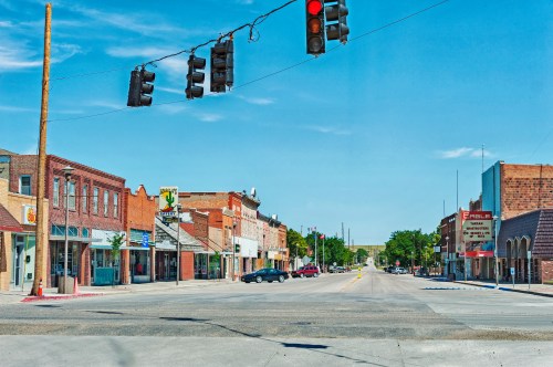 A quiet street scene with shops, a traffic light, and clear blue skies in a small town.