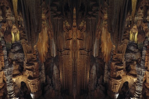 A stunning cave interior with intricate stalactites and stalagmites illuminated by warm lighting.