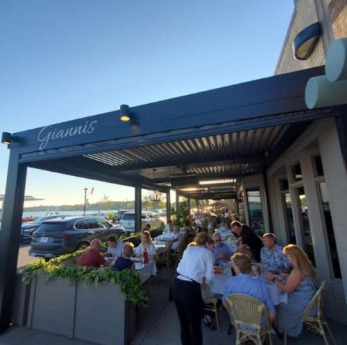 Outdoor dining area at Giannis restaurant, with patrons enjoying meals under a covered patio on a sunny day.