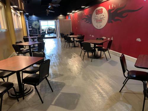 Interior of a restaurant with empty tables and a red wall featuring a logo, creating a casual dining atmosphere.