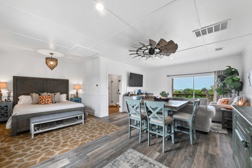 Cozy studio apartment featuring a bed, dining area, and living space with large windows and modern decor.