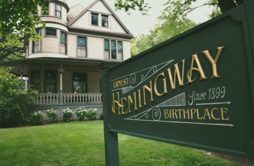 Sign for Ernest Hemingway's Birthplace, featuring a historic house in a lush green setting.