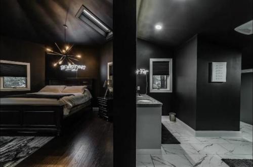 A modern bedroom with dark walls, a stylish light fixture, and an adjoining bathroom featuring marble flooring.