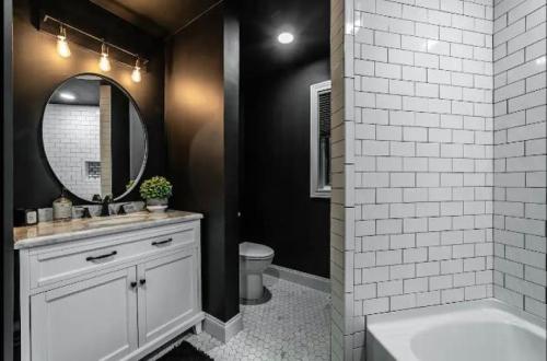 Modern bathroom featuring a round mirror, white subway tiles, a bathtub, and a stylish vanity with a plant.