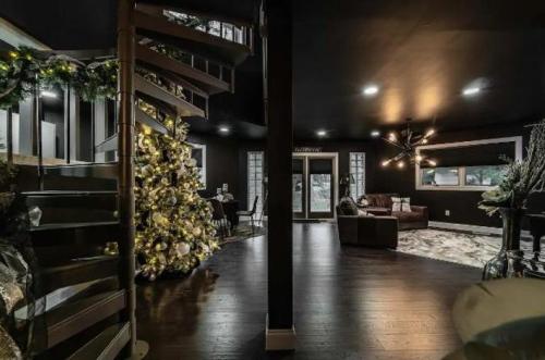 A modern living space with a spiral staircase, decorated Christmas tree, and cozy seating area in dark tones.